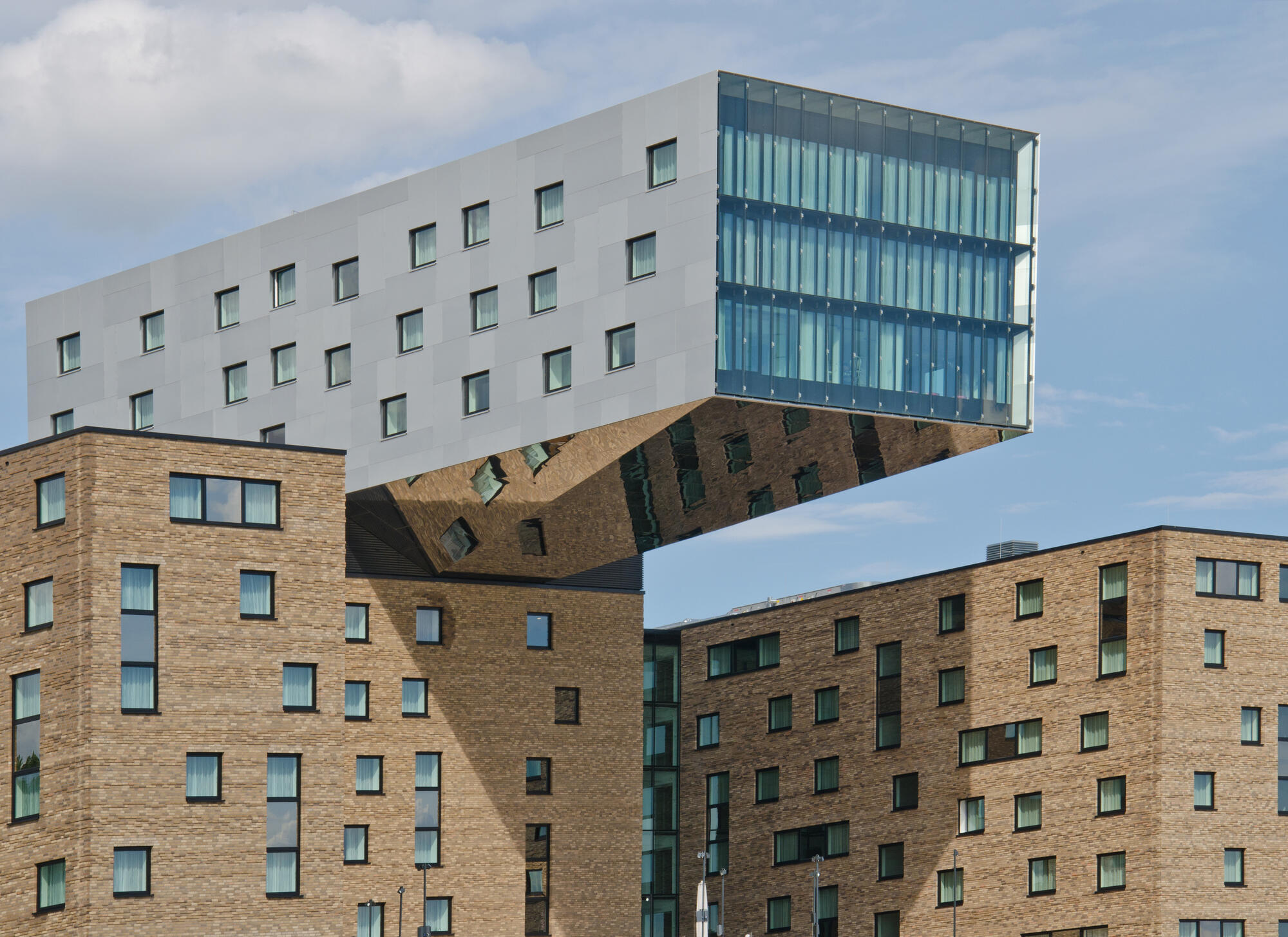 The cantilevered upper section of the nhow hotel above a brick facade on Berlin's Spree riverbank.