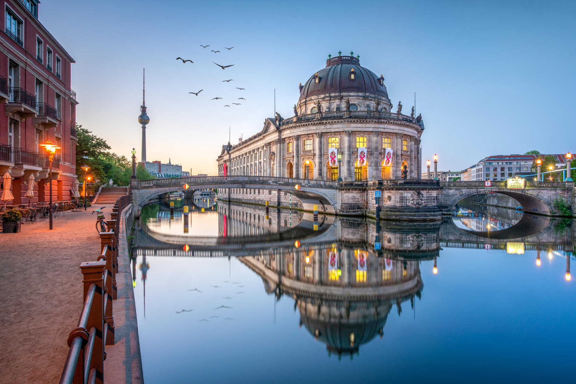 The illuminated Bode Museum and Monbijou Bridge reflected in the Spree, with the TV Tower to the left.