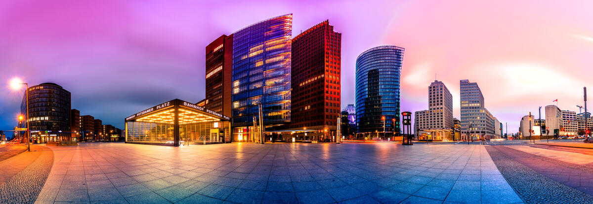An artistically processed panoramic montage of Potsdamer Platz, with a pink evening sky and glass towers.