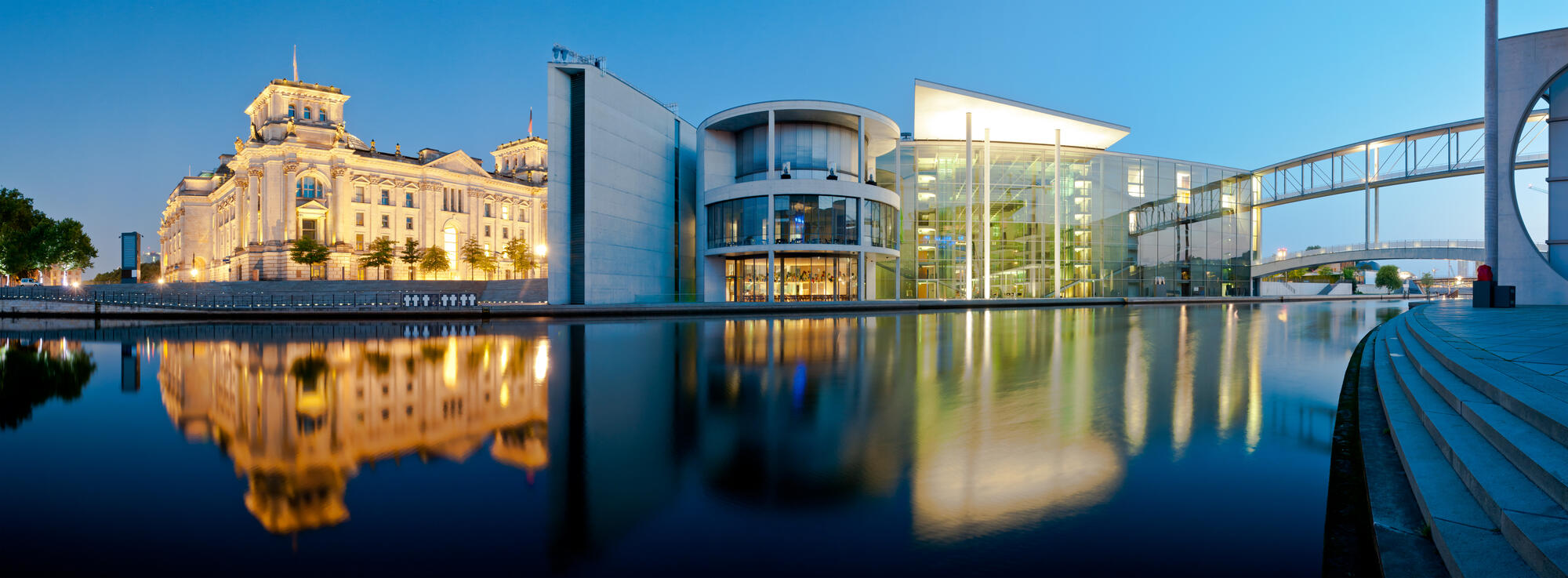 The Reichstag and Paul-Löbe-Haus by the Spree, with illuminated facades and reflections at blue hour.