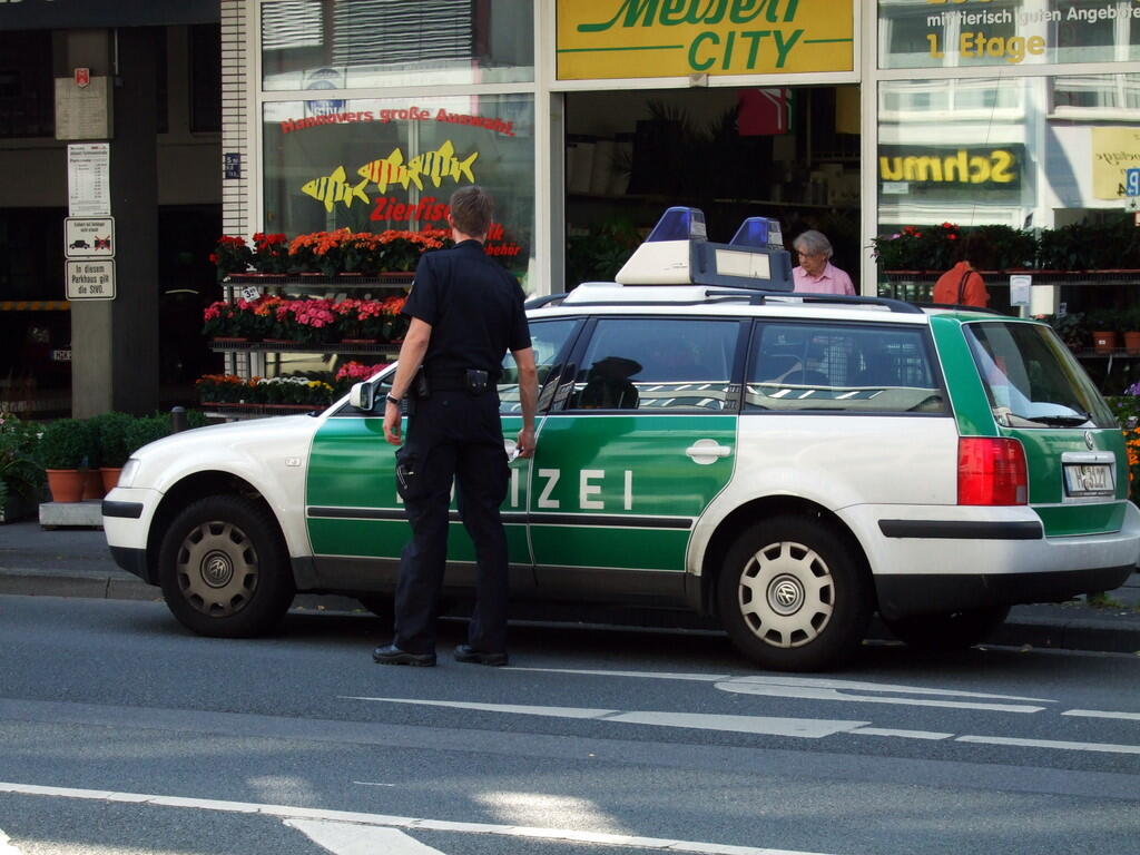Green and white police car with a police officer outside a flower shop