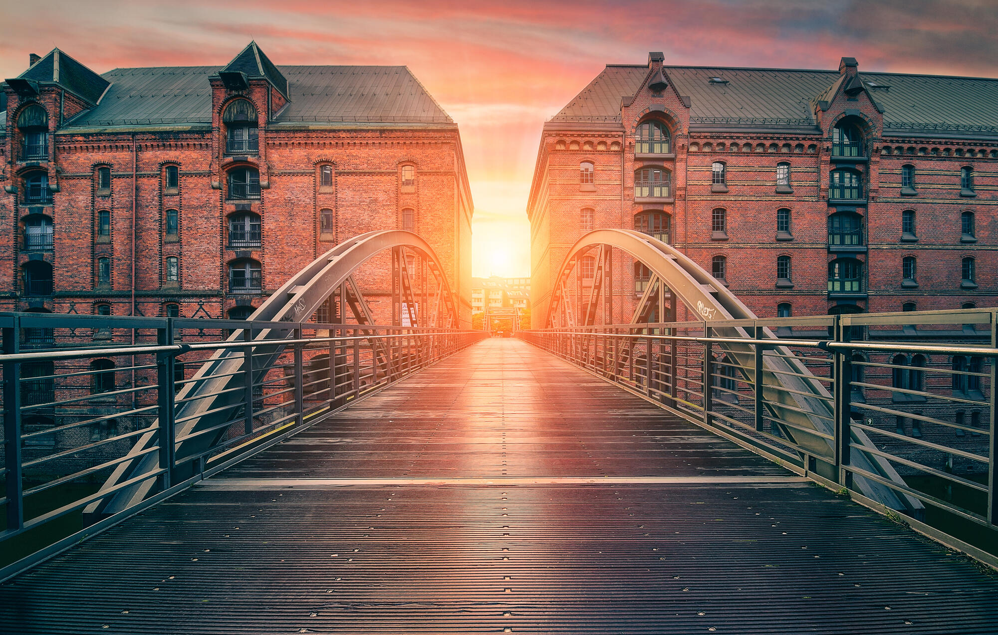 A bridge between Hamburg’s brick warehouses in evening light.
