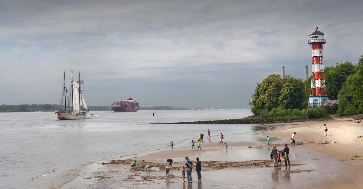 An Elbe beach and lighthouse beneath grey skies.