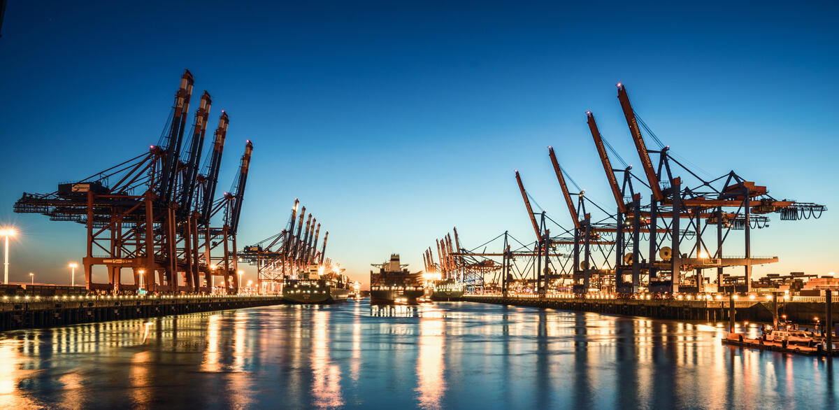 Harbour cranes and reflections in Hamburg at dusk.