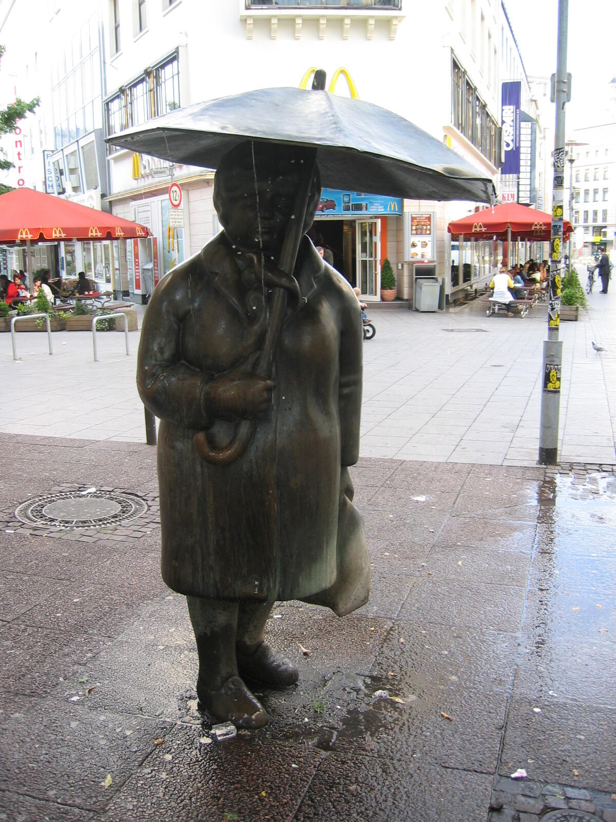 Bronze statue of a woman with an umbrella in the pedestrian zone