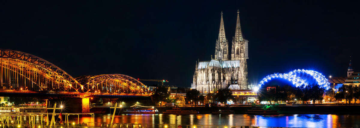 Cologne Cathedral and Hohenzollern Bridge at night.