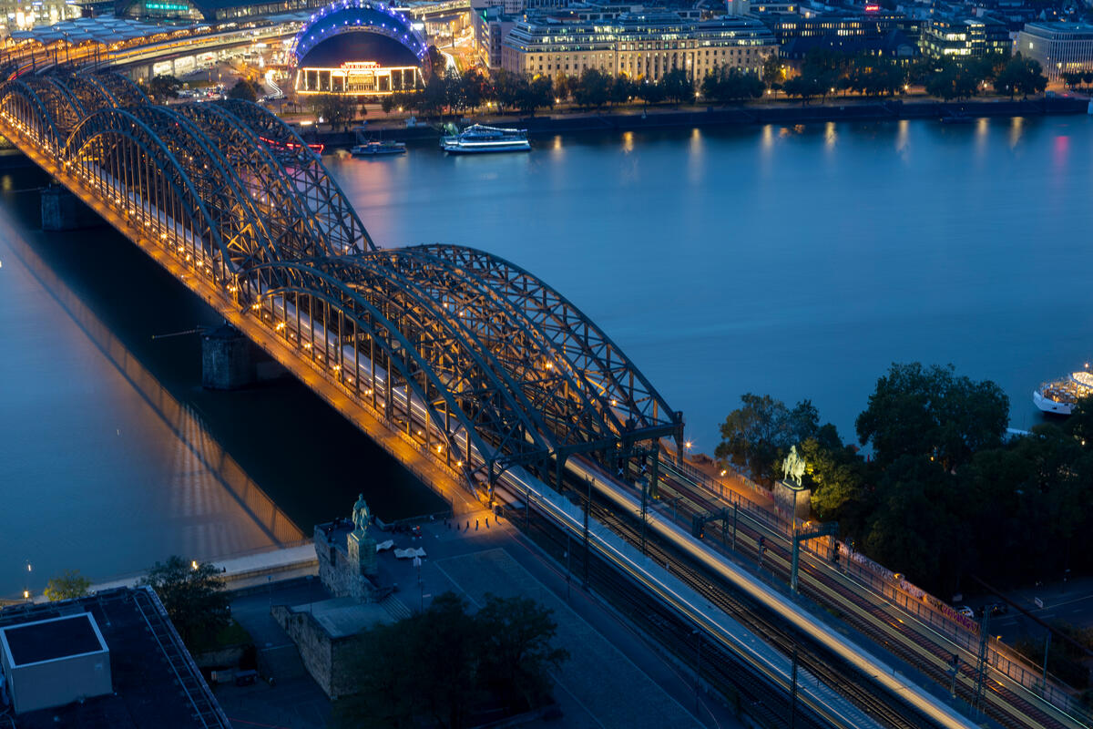 Trains crossing Hohenzollern Bridge in the evening.