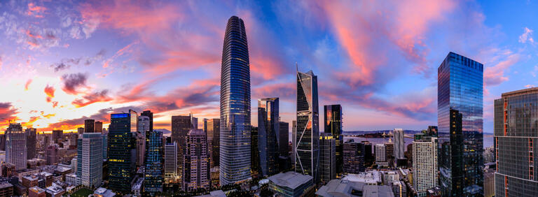 The rounded Salesforce Tower rises above downtown beneath a pink and blue evening sky.