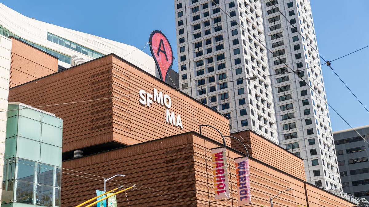 SFMOMA's stepped terracotta-coloured facade, museum lettering and banners in front of neighbouring buildings.