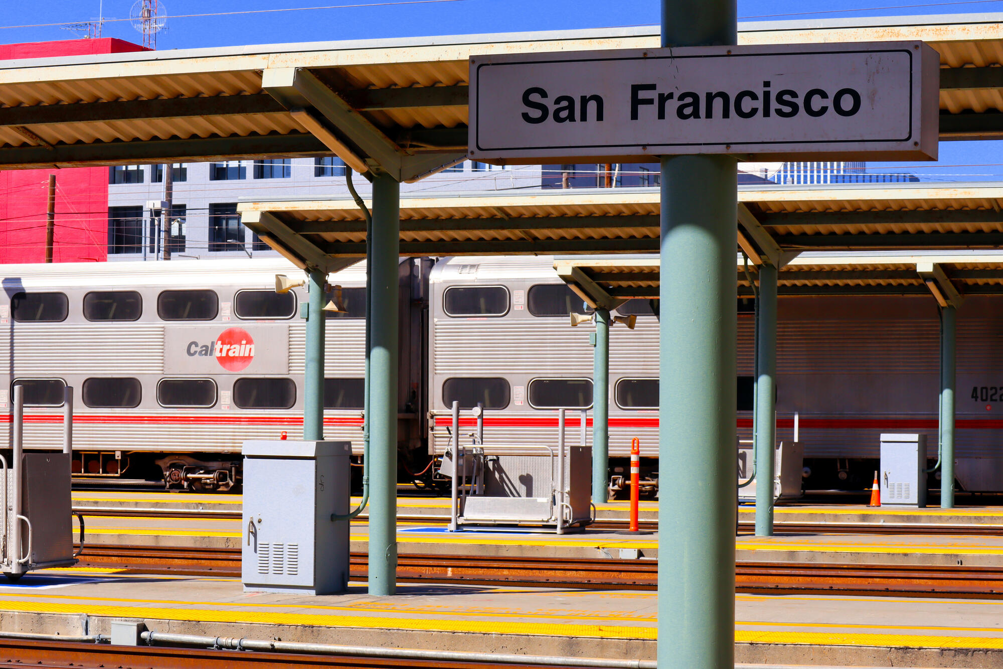 This 2023 image shows a double-deck Caltrain carriage beneath platform canopies and the San Francisco station sign.