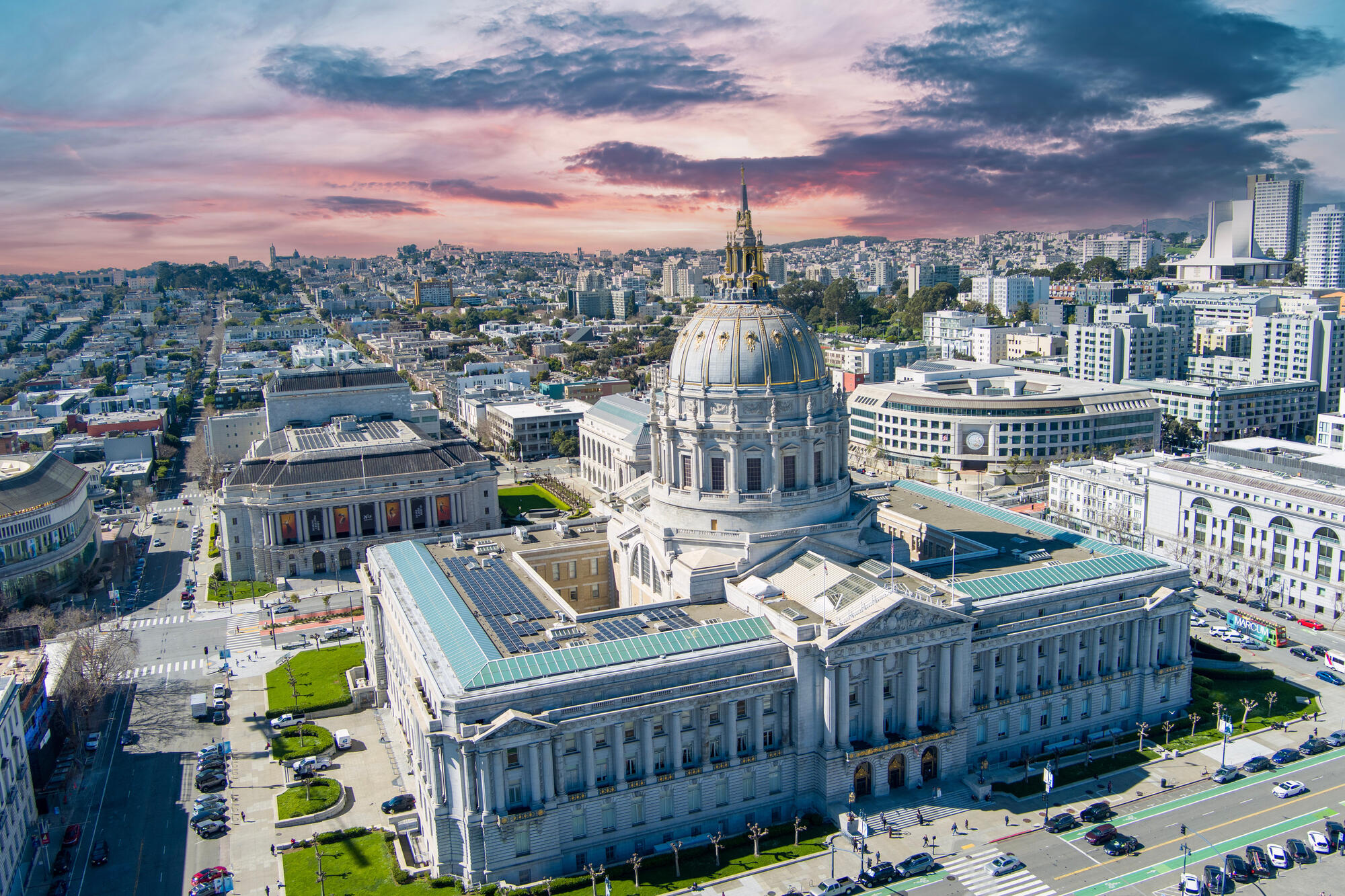 An aerial view reveals City Hall's tall dome, roofs and courtyards among streets and landscaped spaces.
