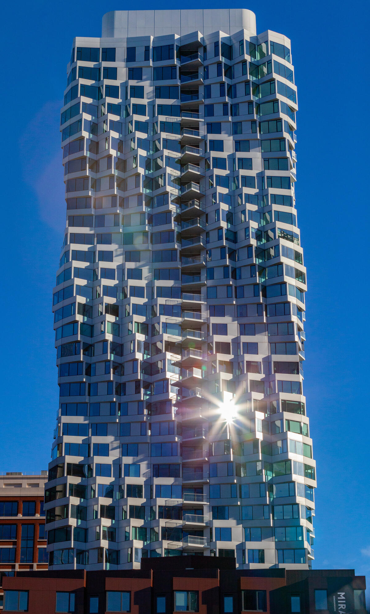 Pale, offset bay windows articulate MIRA Tower's glass facade and create a twisting silhouette.