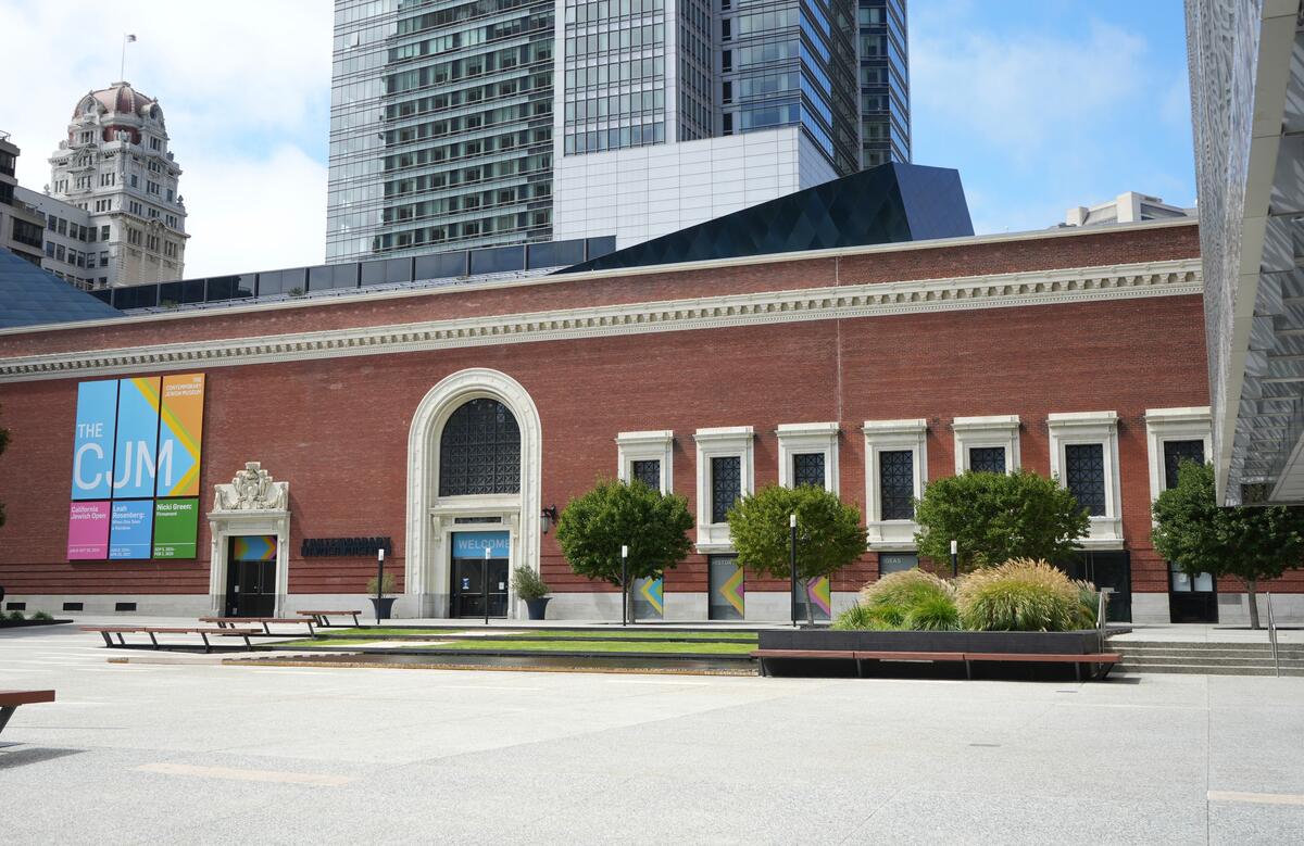 The historic red-brick frontage with its tall arched entrance stands before a dark, angular roof structure.