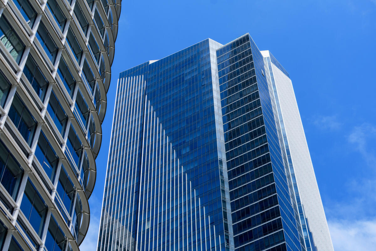An upward view of blue glazing, pale vertical facade strips and the curved edge of Salesforce Tower.