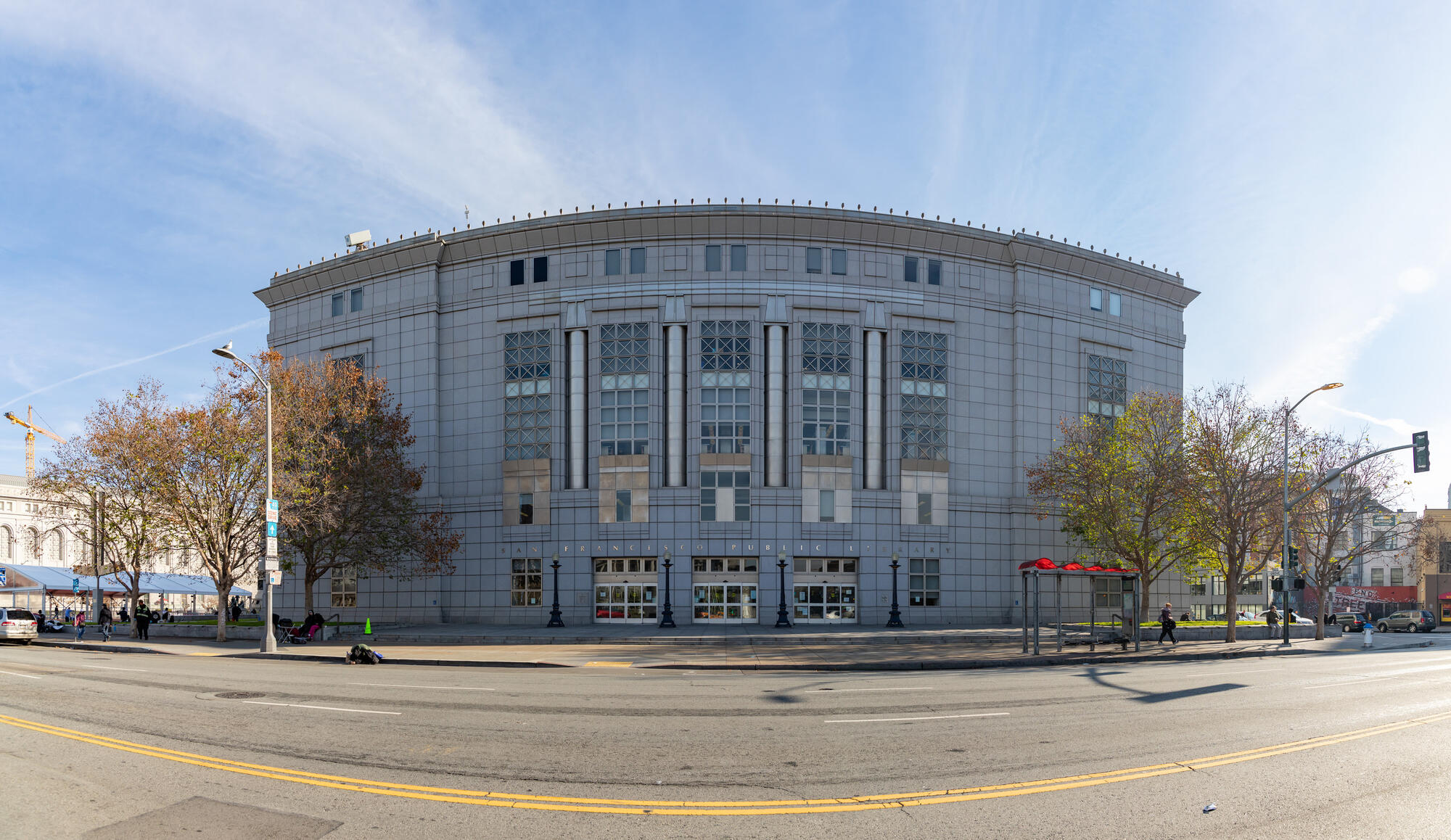 The broad, pale facade of the San Francisco Public Library is divided into tall window bays and slender columns.