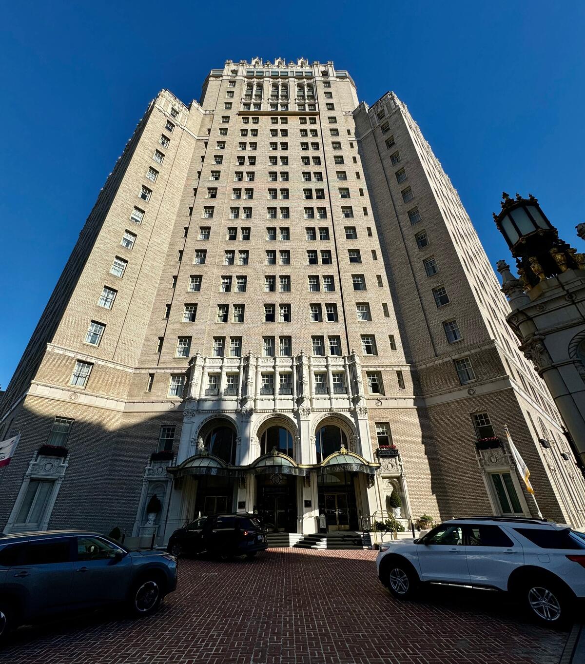A steep upward view of the pale hotel tower, its stepped upper floors and richly detailed entrance.