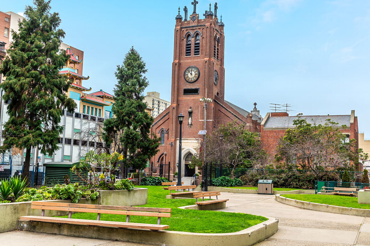 The red church tower, with its clock and pointed decorative details, stands behind the square's planting and seating steps.