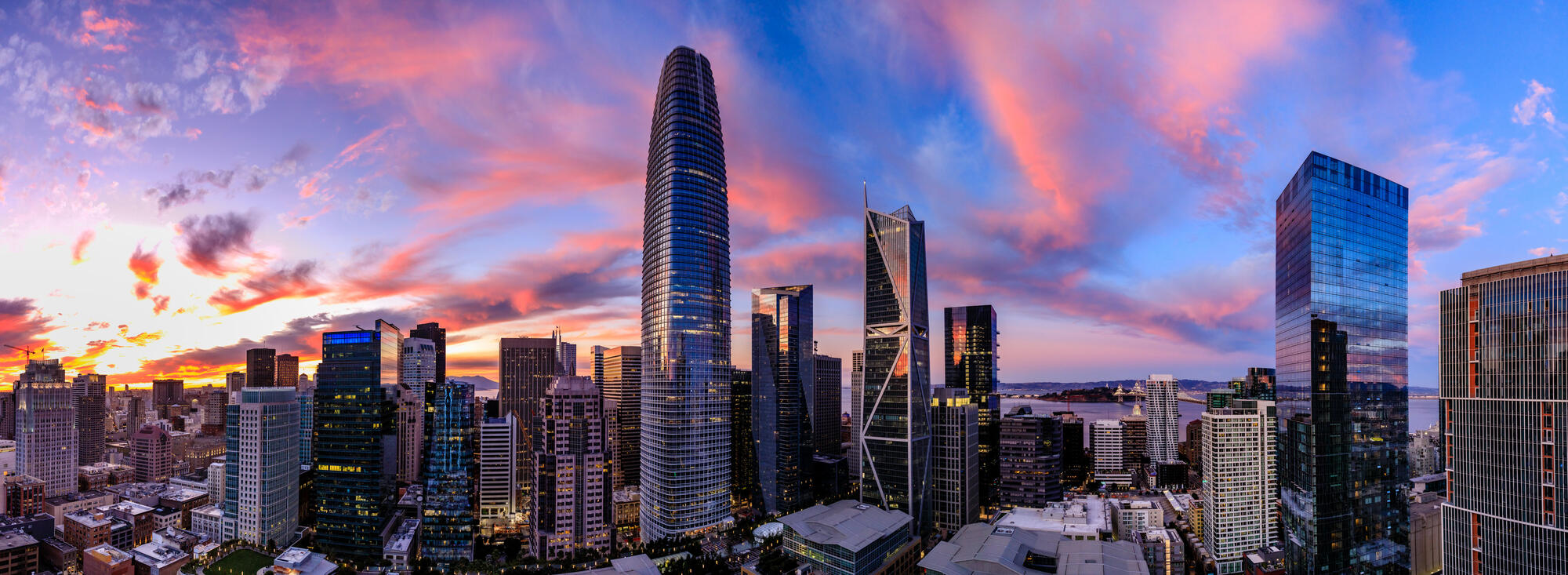 The rounded Salesforce Tower rises above downtown beneath a pink and blue evening sky.