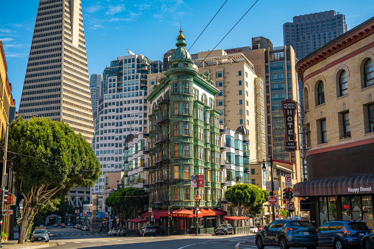 The Sentinel Building's green bay windows and rounded corner turret stand in the streetscape in front of the Transamerica Pyramid.