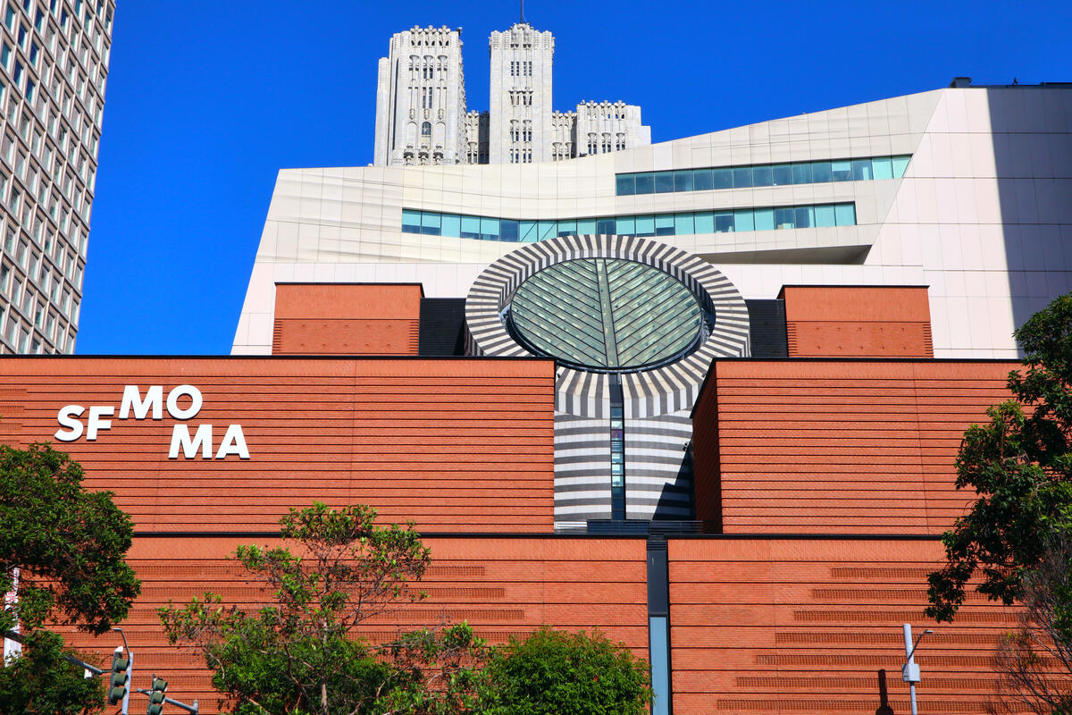 A black and white striped structure with a sloping skylight rises above the museum's red facade.