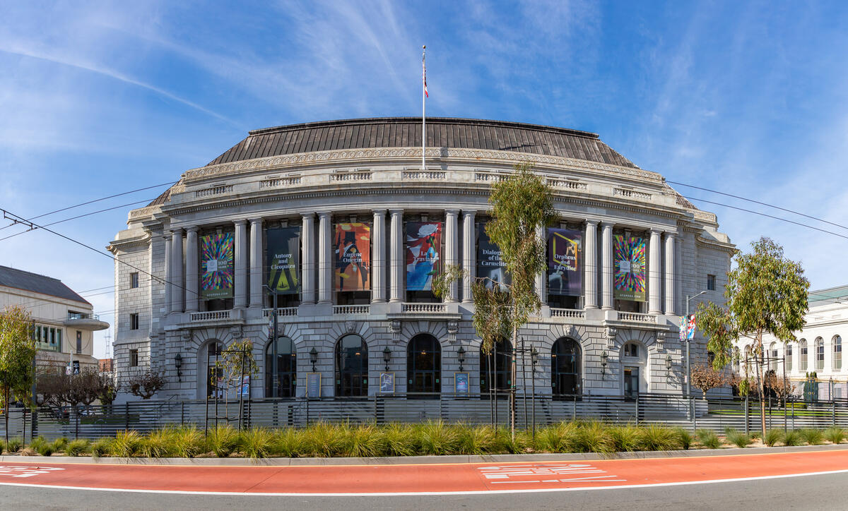 The opera house's columned facade rises above arched entrances and broad street-facing steps.