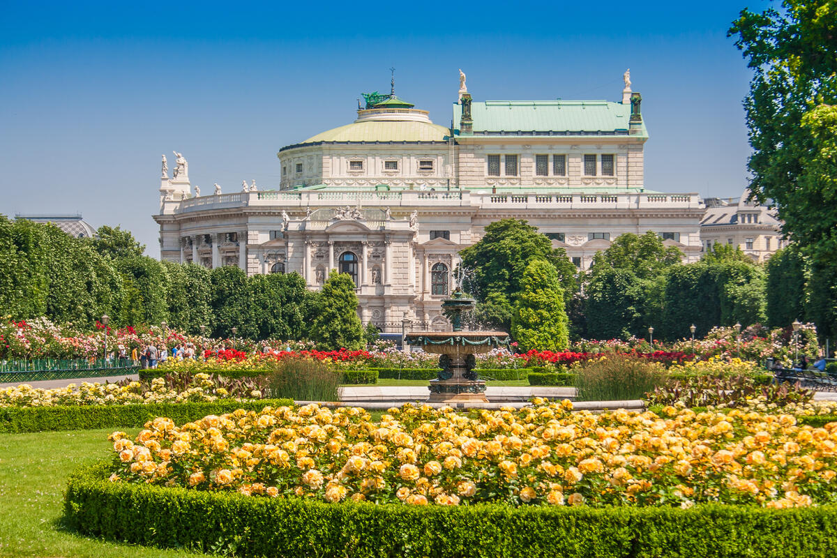 Rose beds and a fountain in Vienna’s Volksgarten, with the Burgtheater behind them.